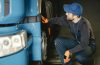 Mechaniker prüft Radkasten eines blauen LKW vor einer Auktion für Nutzfahrzeuge.